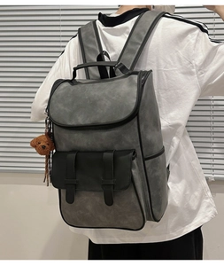Detailed view of gray faux leather vintage backpack with buckle accents and bear charm