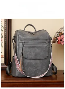 Détail du sac à dos vintage gris en similicuir avec bandoulière tissée et pompon