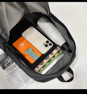 Macro view showing large capacity main compartment of black checkered nylon backpack