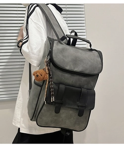 Detailed view of grey and black PU backpack featuring side teddy bear charm and twin pockets