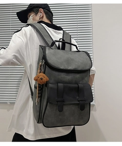Detail view of large PU leather backpack with front buckle pockets and plush bear charm
