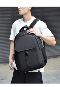 Man wearing a large black minimalist business backpack against a modern grey wall