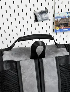 Close-up of the reinforced top handle and breathable mesh shoulder straps on a grey backpack