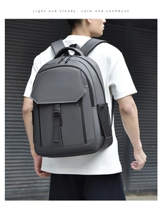 Gray business backpack with flap buckle closure and breathable straps worn by a model