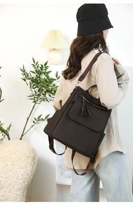 Detail of dark brown waffle texture backpack featuring leather tassels and side pockets