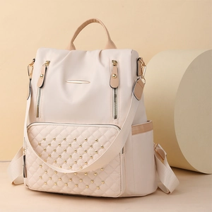 Detail des cremefarbenen Rucksacks mit Karosteppung und goldenen Nietendetails