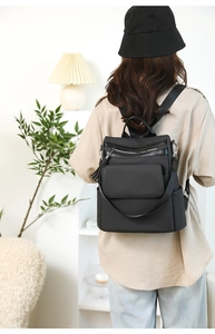 Detail of black woven texture backpack with fringe tassels on model in home setting