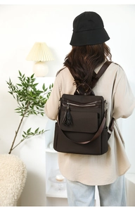 Close-up of deep coffee brown backpack featuring woven texture, tassel and large capacity