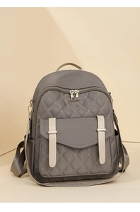 Détail du sac à dos matelassé gris avec fermetures dorées et sangles blanches