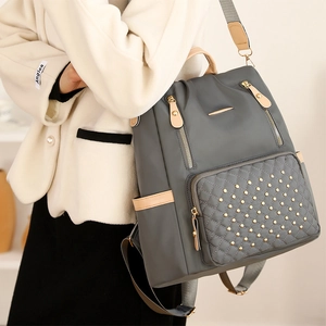 Detail des grauen Stepprucksacks mit goldenen Nieten und glattem Lederbesatz-Finish