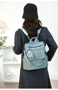 Close-up of light blue textured backpack with tassel detail and functional pockets