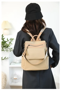 Detail of khaki woven backpack with fringe tassel and brown leather trim on model