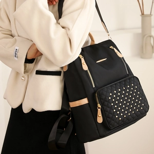 Detail eines gesteppten schwarzen Nylonrucksacks mit Goldnieten und Metallzipper