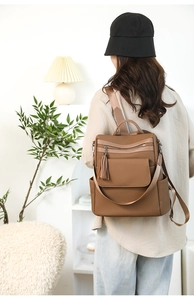 Detail of vintage brown leather backpack with tassel zippers and woven texture surface