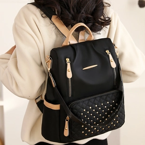 Detail des gesteppten Rucksacks mit goldenen Nieten und beigem Lederbesatz auf Schwarz