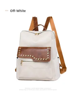Close-up of white oxford printed fabric backpack with brown leather trim and gold studs
