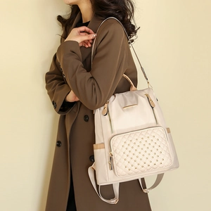 Detail eines beigen Stepprucksacks mit Goldnieten und Metallbesatz am Freizeitoutfit