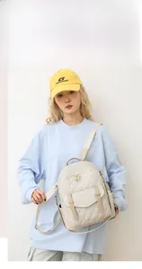Sac à dos matelassé beige pour femme avec boucles brunes, porté par un mannequin