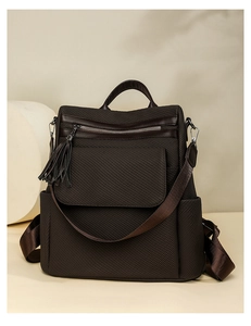Detail of dark brown leather backpack featuring fringe zippers and woven straps