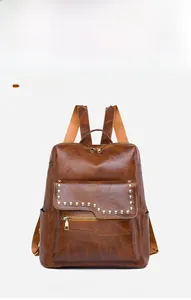 Detailed view of brown PU leather backpack with gold studs and Oxford fabric texture