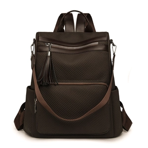 Front view of a dark brown woven texture backpack with tassel and multiple pockets