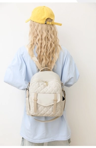Vue détaillée d'un sac à dos mode matelassé crème porté par un mannequin en extérieur