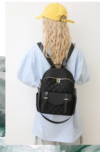 Détail du sac à dos en nylon noir matelassé avec zips dorés et poche à double boucle