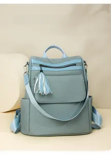 Detailed view of light blue textured backpack with stylish tassel charm and side pocket