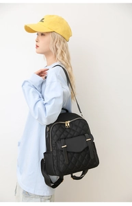 Détail d'un sac à dos noir matelassé avec fermetures éclair dorées et poche latérale