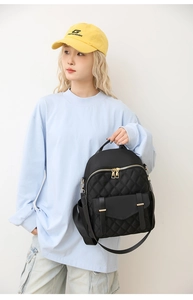 Détail d'un mini sac à dos noir matelassé avec des fermetures éclair dorées