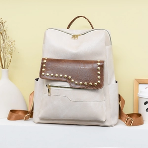 Close-up of stylish PU leather backpack with gold rivets and contrast color pockets