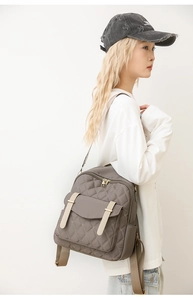 Détail du sac à dos gris foncé matelassé avec sangles crème et poche latérale pratique