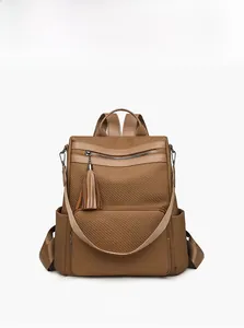 Close-up of brown textured fabric backpack with leather trim and stylish tassel detail