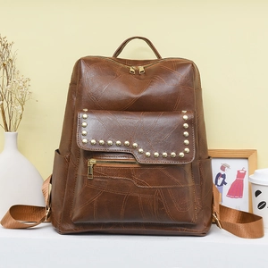 Detailed close-up of brown PU leather backpack featuring vintage rivets and side pockets