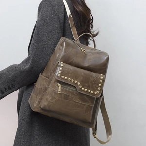 Detailed view of vintage brown leather backpack with leaf vein stitching and gold rivets