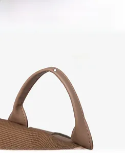 Detail of ergonomic brown leather handle with mesh stitching on vintage backpack