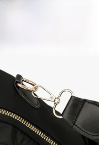 Détail de la bandoulière amovible avec anneau en D doré et texture matelassée sur le sac