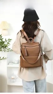 Detailed view of brown textured backpack with stylish tassels and handle on model