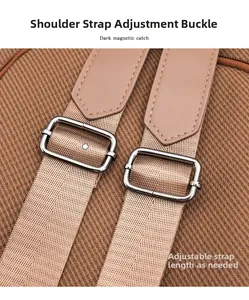 Detail of adjustable canvas shoulder strap with silver metal buckle on brown backpack