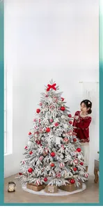Detailed view of luxury flocked Christmas tree with red ornaments and snowy PE leaves
