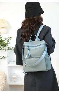 Detail of greyish blue fashion backpack with tassel zipper and durable woven texture