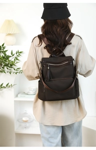 Detail of dark brown textured backpack with tassel decor and adjustable wide shoulder straps