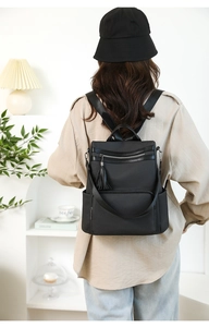 Fashionable black backpack with fringe zipper shown on model in minimalist interior