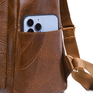 Close-up of side pocket on brown pebbled PU leather backpack holding a blue smartphone