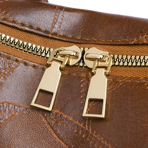 Close-up of golden double zippers and world map print on brown PU leather backpack