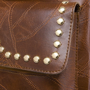 Detailed macro view of vintage brown PU leather with gold studs and decorative stitching