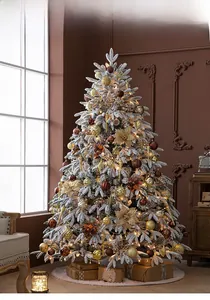Macro view of snow-flocked Christmas tree with gold ornaments and warm LED lights