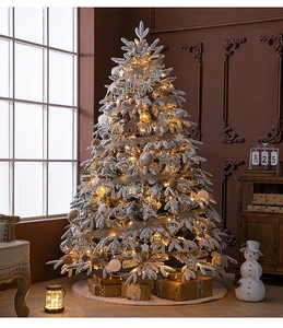 Detail of flocked snow Christmas tree with warm lights and festive wooden ornaments