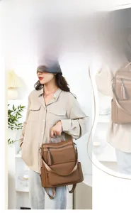 Detail view of brown woven backpack showing side pocket and decorative leather tassel