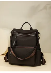 Detail of dark coffee woven backpack with brown leather trim and stylish tassel accents